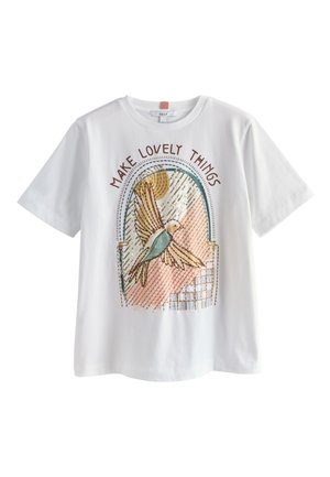 Hvid t-shirt med korte ærmer med en farverig fugl, der flyver i et buet vindue, og teksten "Make Lovely Things" ovenover.
