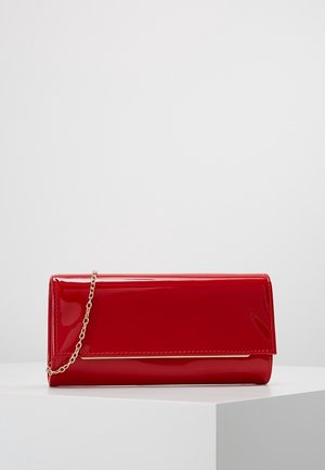 Lesklá červená obdélníková psaníčko s řetízkovým zlatým popruhem a tenkým zlatým akcentem na předním klopu na bílém povrchu.