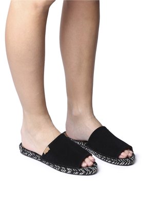 Sandales à glissière en suede noir avec un design à bout ouvert, présentant une semelle extérieure tissée texturée dans un motif noir et blanc.