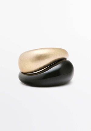 Guld- og sorte keramiske ringe, glatte og afrundede. Den guld ring har en mat overflade, mens den sorte ring har en blank overflade.
