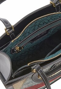 Sac à main en cuir noir avec fermeture éclair dorée, intérieur en tissu en tilleux à motifs, de nombreux compartiments et doubles poignées avec surpiqûres blanches.