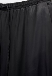Pantalon ample en tissu noir avec une taille élastique et un cordon de serrage à l'avant.