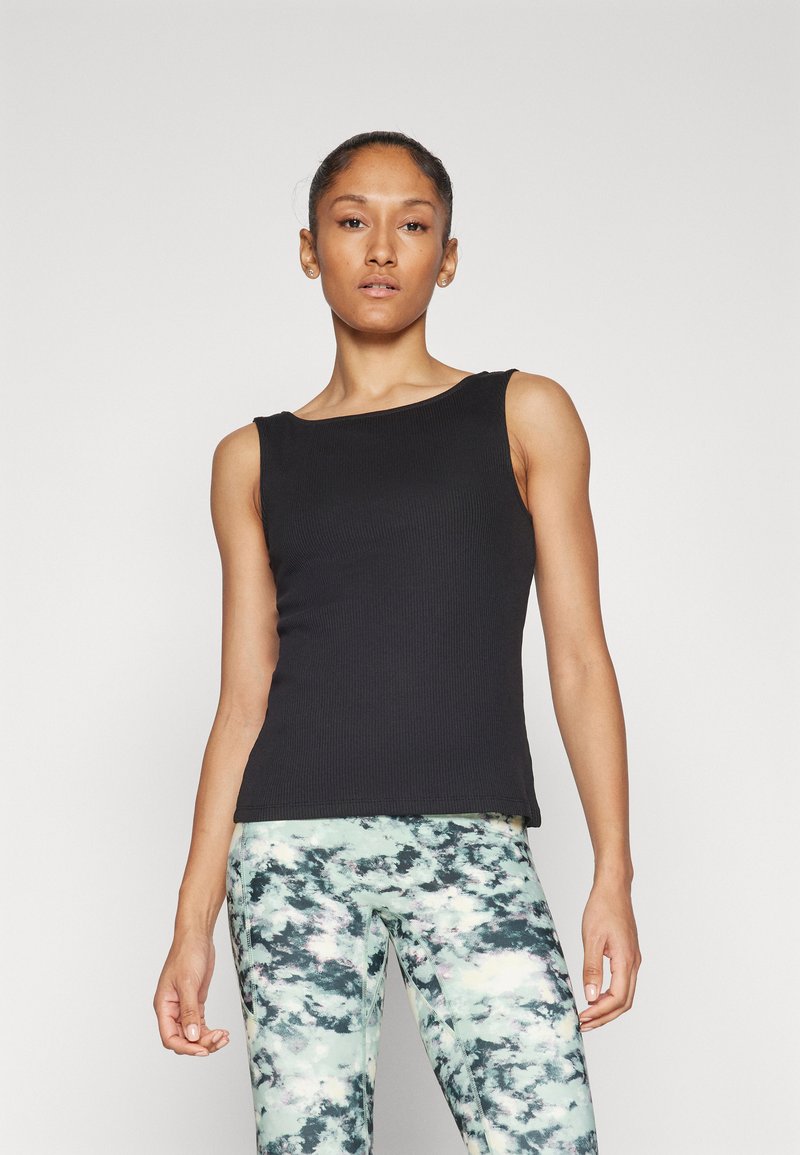 Top in cotone nero a coste con scollatura rotonda, design aderente e senza maniche, abbinato a leggings verde menta con un motivo a nuvole.