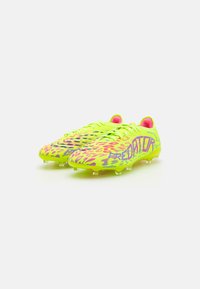 Bottes de football en néon jaune vif avec des accents roses. Surface texturée avec des motifs variés. Conçues pour améliorer l'adhérence et les performances.