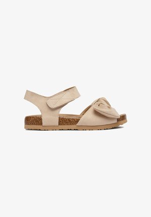 Beige offene Sandale mit Korksohle, verstellbarem Knöchelriemen und einer Stoffschleife am vorderen Riemen.