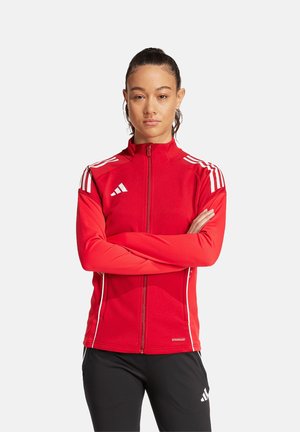 Giacca sportiva rossa con zip sul davanti, colletto alto e tre strisce bianche sulle spalle. Include dettagli bianchi a contrasto e logo.