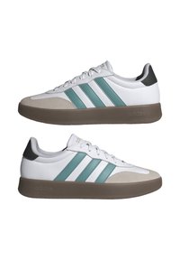Zapatillas blancas con Rayas en teal, punta de ante y suela de goma marrón. Incluye un acento negro en el talón y sistema de cordones clásico.