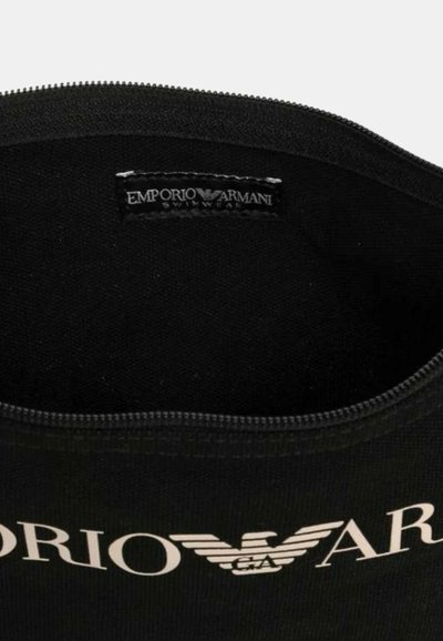 Bolsa de natación negra hecha de tela suave, con un cierre de plata y un logo blanco prominente que dice "Emporio Armani" en el interior.