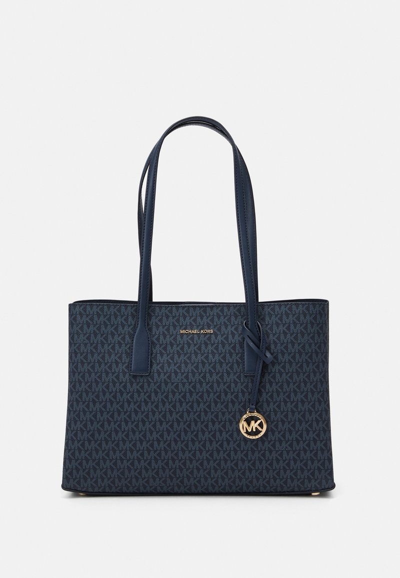 Sac cabas bleu marine Michael Kors avec doubles anses d’épaule, motif répétitif du logo MK, breloque dorée avec logo et inscription « Michael Kors » sur le devant.