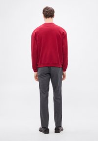 Μπλούζα φούτερ βυσσινί με μακριά μανίκια, στρογγυλό λαιμόκοψη και ριμπ μανσέτες, συνδυασμένη με γκρι παντελόνια. Απλός, καθημερινός σχεδιασμός με υφή.