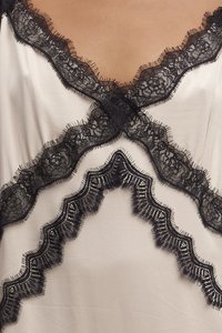 Tops s čipkovaným lemovaním, vyrobený z krémovej látky s čiernymi zvlnenými čipkovými akcentmi. Pozoruhodné textúry a zložitá čipková aplikácia posúva dizajn na vyššiu úroveň.