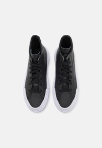 Μαύρα ψηλά αθλητικά παπούτσια από λείο δέρμα με λευκές καουτσούκ σόλες, διαθέτοντας μαύρες κορδόνες και λεπτές ραφές.