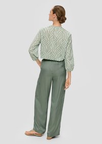 Groene blouse met een patroon, ballonsleuven en een ontspannen pasvorm, gecombineerd met bijpassende wijde broek met zijzakken en een zachte textuur.