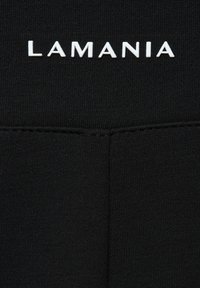 Fekete, sima textúrájú anyag, amelyen a "LAMANIA" szó fehér, kiemelkedő betűkkel szerepel. A design minimalista, további minták nélkül.