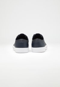 Granatowe skórzane sneakersy z białymi gumowymi podeszwami, gładka tekstura, zaokrąglony kształt i minimalistyczny design. Nie mają widocznych elementów metalowych ani wzorów.