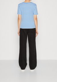 Blauw-wit gestreepte T-shirt met korte mouwen en ronde hals, gecombineerd met zwarte wijde broek. Eenvoudig ontwerp en een gladde textuur.
