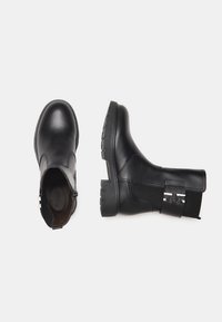 Black leather ankle boots with a rubber sole, rounded toe, elastic side panel, and silver hardware detail on the ankle strap.