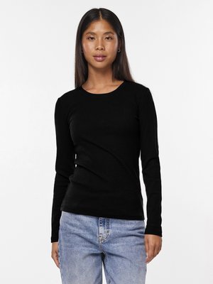 Camiseta ajustada de manga larga negra hecha de tela acanalada con un escote redondo. Combinada con unos vaqueros de denim azul claro, mostrando un estilo casual.