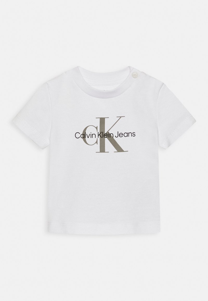 Maglietta corta in cotone bianco a maniche corte con scollo rotondo, caratterizzata dal logo "Calvin Klein Jeans" in nero e grigio. Dettaglio con bottone a pressione sulla spalla.