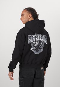 Black hoodie with a large graphic of an eagle and "BENFICA" in white lettering on the back. The fabric appears thick and soft.
