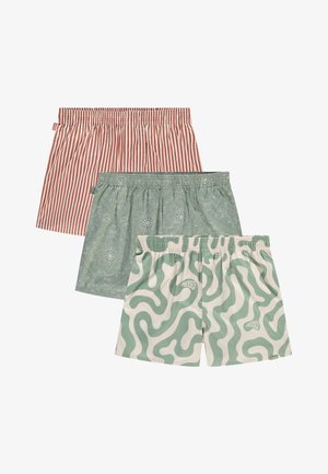 Tre paia di pantaloni corti da uomo: il primo con righe rosse e bianche, il secondo in paisley verde, il terzo con motivi ondulati crema e verdi, tutti con vita elastica.