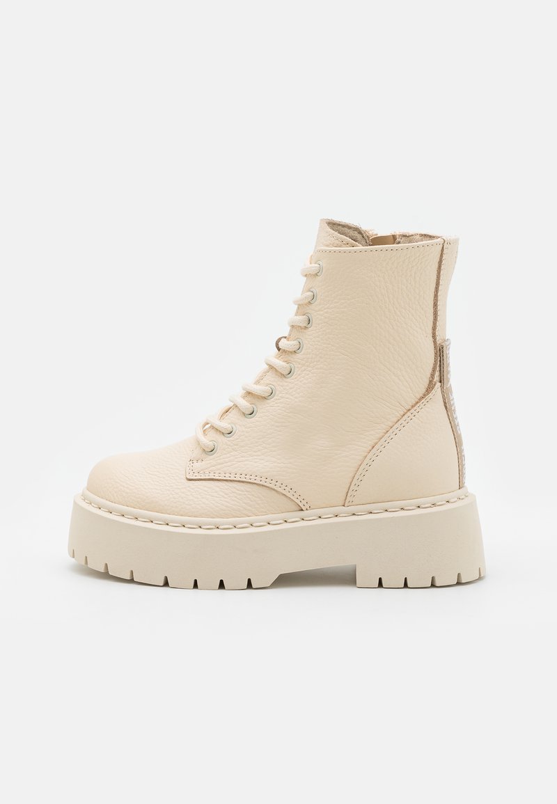 Bottines en cuir beige avec un laçage sur le devant, semelle plateforme épaisse et détails en panneaux texturés sur le côté. Accents cousus le long de la semelle.