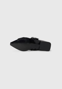 Black high-heeled shoe with a pointed toe, textured surface, and a chunky heel. Features silver hardware accents and sleek, smooth design.