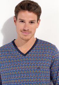 V-neck t-shirt in multicolored chevron pattern, featuring blue, red, and yellow accents, with a navy collar and soft cotton material.
