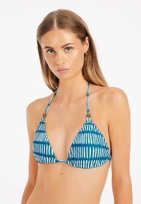 Sininen kolmio-bikini yläosa, jossa on valkoisia pystysuoria raitoja. Mallissa on ohuet hihnat ja pieniä pyöreitä yksityiskohtia kaula-aukossa.