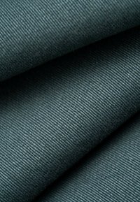 Tejido de color verde oscuro con una textura estriada, doblado, mostrando su durabilidad y un acabado suave.