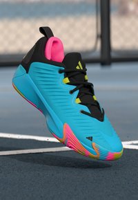 Blue athletic shoe with black accents, bright pink collar, and yellow laces. Features a textured upper and a multicolored rubber sole.