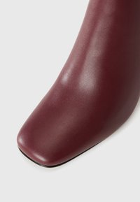 Vyniojo odos kulkšnies botas, su kvadratiniu pirštu, lygia tekstūra, minimalistišku dizainu ir plona juoda interesa.