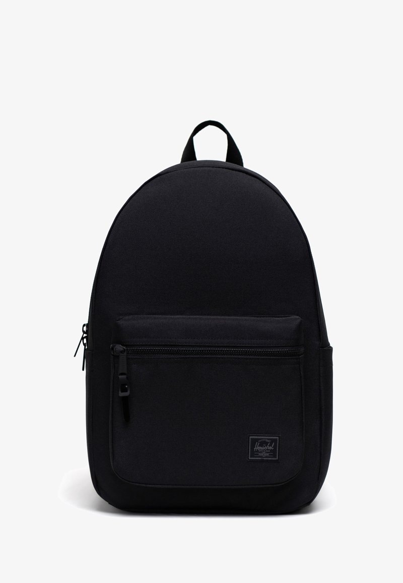 Musta kangaskärry, jossa on pyöristetty muoto, vetoketjullinen etutasku ja yläkahva. Alhaalla etupaneelissa on logotagi.