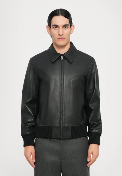 Veste bomber en cuir noir avec fermeture éclair à l'avant, large col et poignets et ourlet côtelés. Texture lisse et coupe ajustée.