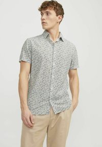 Camicia a maniche corte con bottoni in tessuto leggero, con un motivo floreale in tonalità di blu e bianco. Taglio dritto, colletto standard e vestibilità rilassata.