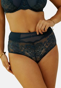 Culotte en dentelle taille haute de couleur bleu sarcelle avec des motifs floraux, des panneaux en mesh et des accents en satin. Présente une taille lisse avec un clip décoratif.