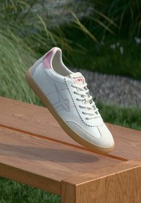 Λευκό δερμάτινο sneaker με ροζ λεπτομέρειες, σύστημα κορδονιών, υφασμάτινη μύτη και σόλα από καουτσούκ. Διαθέτει ραμμένα στοιχεία και λογότυπο στη γλώσσα.