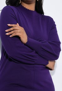Maglione viola a maglia con colletto ondulato, maniche lunghe a sbuffo con polsini a costine e design aderente per una silhouette elegante.