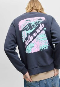 Sudadera navy con un diseño gráfico colorido que presenta montañas y el texto "Colorado" impreso en la parte trasera. Puños y dobladillo acanalados.