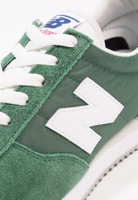 Gröna sneakers med ovandel i tyg och mocka, vita snören, stor vit logotyp och en texturerad gummisula.