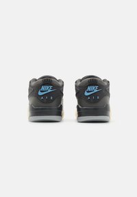Baskets Nike Air avec une tige noire, un logo bleu, un col rembourré, des détails texturés, et une semelle intermédiaire crème et une semelle extérieure grise.
