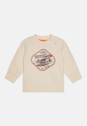 Crèmekleurige sweatshirt met een ronde halslijn, voorzien van een grafische print van een vliegtuig en "TIMBERLAND." Inclusief knoopaccenten op de schouder.