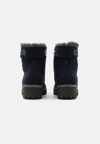 Bottines en daim bleu marine avec une doublure en fourrure grise texturée, des fermetures éclair latérales et des semelles en caoutchouc robustes pour une meilleure adhérence et durabilité.