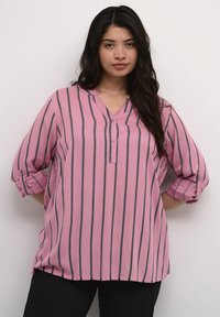 Rosa randig blus med uppvikta ärmar, med en v-ringning och knapprad fram, tillverkad av ett lätt tyg med en mjuk textur.