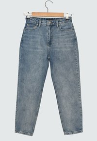 Jeans de mezclilla de tiro alto en azul claro, con bolsillos frontales y cierre de botón, colgando de una percha de madera sobre un fondo uniforme.