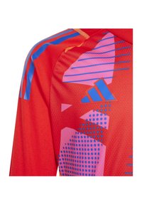 Rode sportshirt met een gepatterneerd ontwerp van roze en blauwe geometrische vormen, een gestructureerde stof en blauwe streepaccenten.