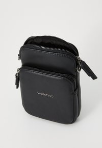 Black leather crossbody bag with two zippered compartments, featuring a smooth texture and silver hardware. Logo imprinted on the front.