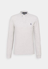 Långärmad polo i ljusgrått, tillverkad av strukturerad tyg. Har en placket med två knappar och ett broderat marinblått logotyp på bröstet.