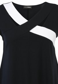 Black top featuring a diagonal white band across the chest, with a V-neck and soft fabric texture. Label visible at the neckline.