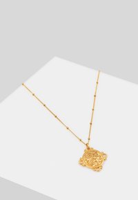 Collana in oro con un pendente rotondo raffigurante un leone, sospesa su una catenina decorata con piccole perle rotonde, dalla texture liscia e dalla finitura lucente.